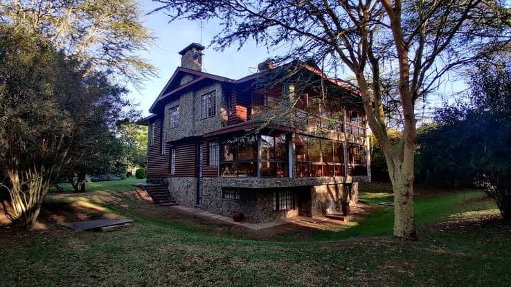 Exterior of Mayhill West, a stone-and-timber chalet set among mature trees at Great Rift Valley Lodge in Naivasha